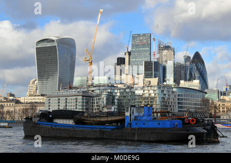 Eine alte Arbeiten Thames River Boot vor der finanziellen Herzen der Stadt mit der berühmten Skyline einschließlich aller bekannten Gebäuden vertäut. Stockfoto