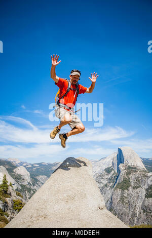 Ein Mann in der Luft an der Glacier Point springen mit Half Dome im Hintergrund, Yosemite National Park, Kalifornien Stockfoto