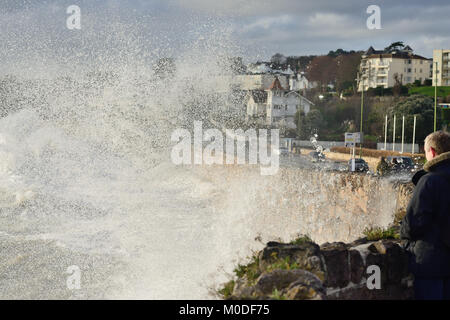 Menschen beobachten von einem sicheren Ort aus, wie Wellen während einer stürmischen Flut in Torquay, South Devon, gegen die Meeresmauer krachen. Stockfoto