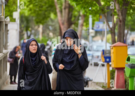 Isfahan, Iran - 24. April 2017: Zwei muslimische Frauen, in einem Schwarzen islamischen Tschador, sprechen Sie gekleidet, während entlang der Straße der Stadt. Stockfoto