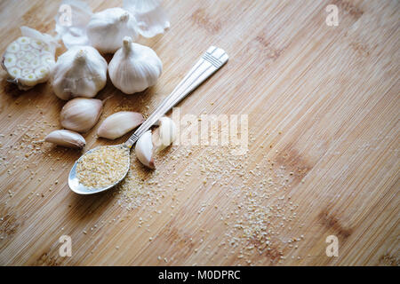 Knoblauch Zwiebeln, Knoblauchzehen und Knoblauch Pulver auf einem hölzernen Hintergrund Stockfoto