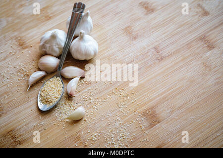 Knoblauch Zwiebeln, Knoblauchzehen und Knoblauch Pulver auf einem hölzernen Hintergrund Stockfoto