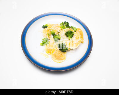 Ravioli angemacht mit Olivenöl geriebenem Parmigiano Reggiano Käse Broccoli und schwarzer Pfeffer auf einem blauen Schild mit weißem Hintergrund umrandete Stockfoto