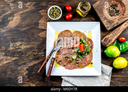 Rohes Rindfleisch Carpaccio auf weiße Platte, Holz- Hintergrund, Ansicht von oben, kopieren. Stockfoto