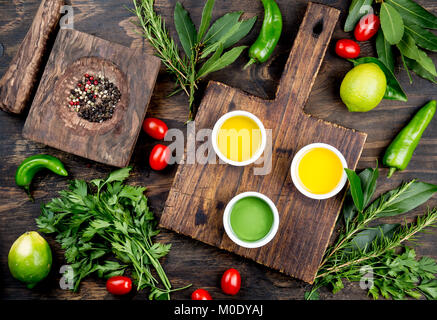 Öle, Gewürze und Kräuter. Trauben, Oliven und Mais Öle frische Kräuter Zitronen, Paprika. Ansicht von oben. Stockfoto