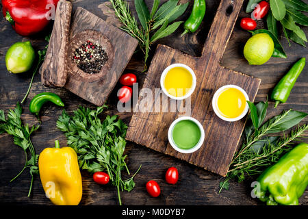 Öle, Gewürze und Kräuter. Trauben, Oliven und Mais Öle frische Kräuter Zitronen, Paprika. Ansicht von oben. Stockfoto