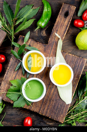 Öle, Gewürze und Kräuter. Trauben, Oliven und Mais Öle frische Kräuter Zitronen, Paprika. Ansicht von oben. Stockfoto