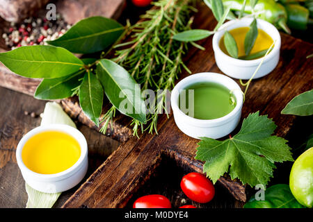 Öle, Gewürze und Kräuter. Trauben, Oliven und Mais Öle frische Kräuter Zitronen, Paprika. Stockfoto