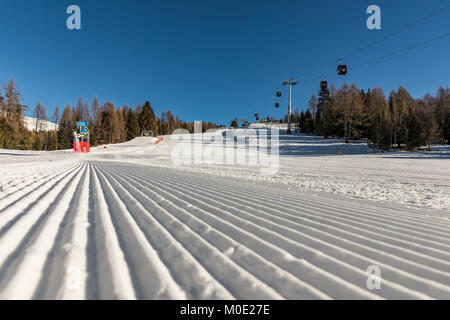 Alpe di Lusia, Italien. Dolomiten, schöne Skigebiet mit schönen Pisten. Leere Skipiste im Winter und blauer Himmel. Vorbereitung der Skipiste. Stockfoto