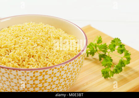 Schüssel ungekochten Alphabet Nudeln auf Holz Schneidebrett - Nahaufnahme Stockfoto