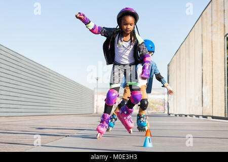 Mädchen lernen Skate mit Inline Skates zu Slalom Stockfoto