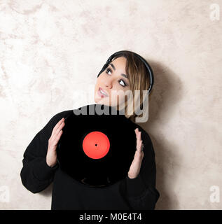 Junge blonde hübsche Frau mit Kopfhörer, mit Vintage vinyl record Red kopieren Speicherplatz auf Etikett Stockfoto