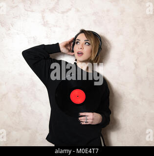 Junge blonde hübsche Frau mit Kopfhörer, mit Vintage vinyl record Red kopieren Speicherplatz auf Etikett Stockfoto