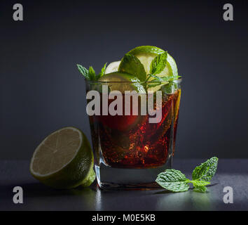 Cola mit Rum, Limette und Minze auf Schwarzen Tisch in der Bar. Stockfoto