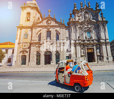 Tuk Tuk mit touristischen vor alten Carmelitas Kirche in Porto, Portugal Stockfoto