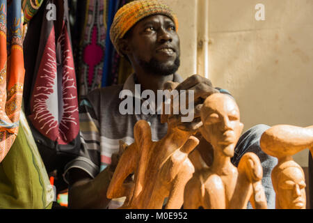 Ein afrikanischer Mann schnitzt Holzfiguren in Senegambia, Gambia Stockfoto