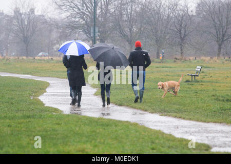 London, Großbritannien. 21. Januar 2018. Fußgänger gehen Sie mit brollies auf Wimbledon Common in gefrierenden Regen und Schneeregen an einem kalten Elend Sonntag Stockfoto