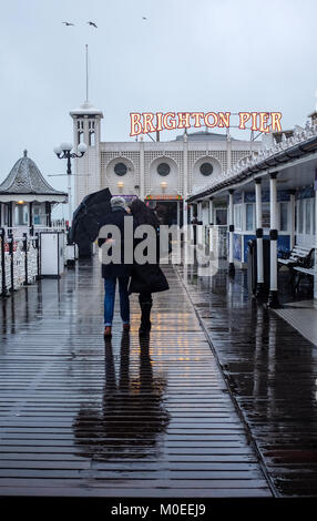 Brighton UK 21. Januar 2018 - Ein paar tapfere der schwere Regen, da Sie für einen Spaziergang gehen heute entlang von Brighton Palace Pier mit einigen Teilen Großbritanniens Prognose mehr Schnee Foto von Simon Dack Credit: Simon Dack/Alamy Leben Nachrichten zu haben Stockfoto