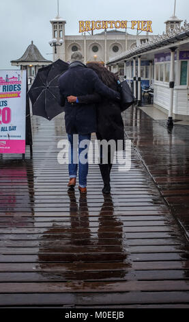 Brighton UK 21. Januar 2018 - Ein paar tapfere der schwere Regen, da Sie für einen Spaziergang gehen heute entlang von Brighton Palace Pier mit einigen Teilen Großbritanniens Prognose mehr Schnee Foto von Simon Dack Credit: Simon Dack/Alamy Leben Nachrichten zu haben Stockfoto