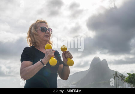 Reife Frau (70-79) Training mit Kurzhanteln an öffentlichen Turnhalle in Ipanema, Rio de Janeiro, Brasilien Stockfoto