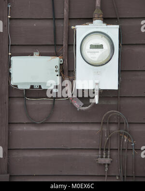 Ein Stromzähler, Telefon und Kabelfernsehen utility Verbindungen auf der Außenseite eines Hauses in der Spekulant, NY USAcables. Stockfoto