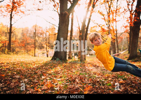 Junge sitzt auf einer Schaukel im Garten Stockfoto