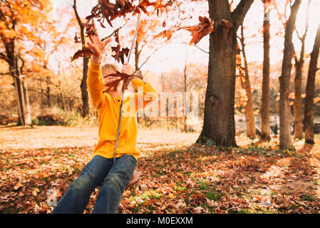 Junge sitzt auf einer Schaukel im Garten Stockfoto