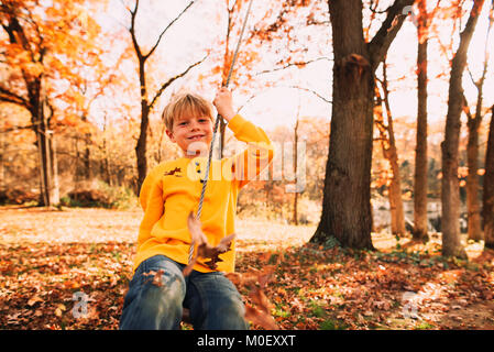 Junge sitzt auf einer Schaukel im Garten Stockfoto
