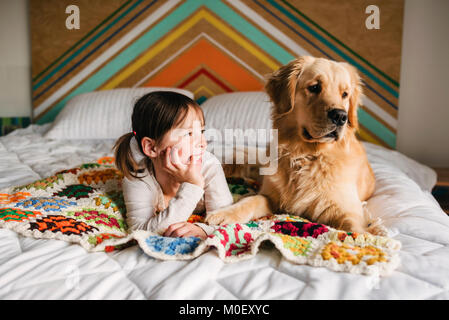 Mädchen liegt auf einem Bett mit ihrem Golden Retriever Hund Stockfoto