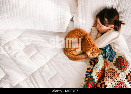 Mädchen in ein Nickerchen auf einem Bett mit ihrer Katze Stockfoto