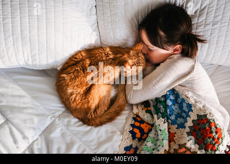 Mädchen in ein Nickerchen auf einem Bett mit ihrer Katze Stockfoto