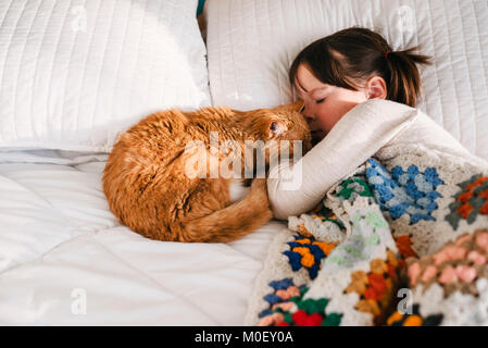 Mädchen in ein Nickerchen auf einem Bett mit ihrer Katze Stockfoto