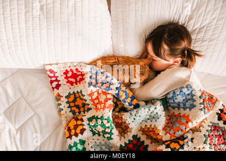 Mädchen in ein Nickerchen auf einem Bett mit ihrer Katze Stockfoto