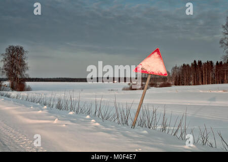 Die warnzeichen durch eine verschneite Straße im Norden Finnlands wurde komplett mit Schnee bedeckt. Vielleicht wird die Warnung über zu viel Schnee. Stockfoto