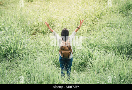 Glückliche junge Reisende Frau Backpacker erhobenen Arm bis zu Himmel genießen einen schönen der Natur an Gras feld grün frische Luft, Freiheit wanderlust Konzept Stockfoto