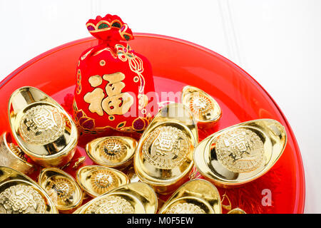 Das chinesische Neujahr ang Pow rotem Filz Stofftasche mit gold Barren in Rot auf weißem Holz Tischplatte, Chinesische Sprache auf Tasche bedeuten Glück und auf Ingots Stockfoto