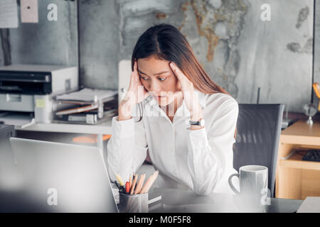 Frustriert asiatischen Geschäftsfrau Abdeckung ihr Gesicht mit beiden Händen und fühlen sich von der Arbeit am Laptop umgekippt auf dem Schreibtisch im Büro, Stress office lifes Stockfoto