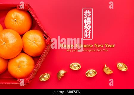 Gruppe von orange Tangerine in der chinesischen Muster Fach mit gold Barren auf dem roten Tisch. der Chinesischen Sprache auf Ingots, wohlhabend und lable bedeuten können Sie über eine p Stockfoto