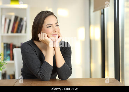 Porträt einer nachdenkliche Frau entspannende durch ein Fenster zu hause suchen Stockfoto