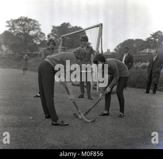 1960, historische, zwei weibliche Schüler Krankenschwestern an ein pflegeheim Hochschule über "Bully-off' oder spielen Sie eine Partie Hockey wieder draußen auf einem Rasenplatz, England, UK. Stockfoto