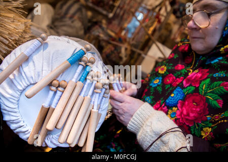 Eine Frau in einem Schal mit einem russischen nationalen Muster Webt Spitze auf Spulen auf Tverskaya Street im Zentrum von Moskau, Russland Stockfoto