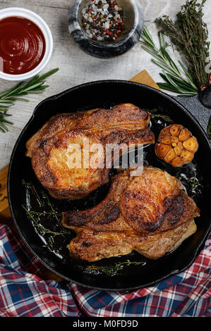 Gebratene Schweinelende steak in der Pfanne mit Tomaten und Gewürzen Stockfoto