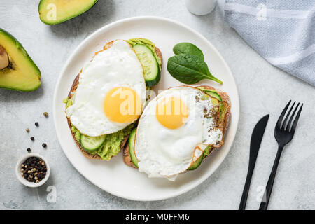 Ei und Avocado Frühstück Toast auf weiße Platte. Tabelle Ansicht von oben. Gesunde Ernährung Diät Konzept Stockfoto