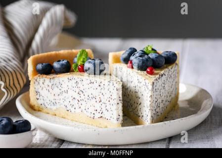 Zwei Scheiben Käsekuchen mit Mohn und Heidelbeeren auf weiße Platte. Detailansicht Stockfoto