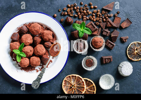 Dunkle Schokolade Trüffel, Kaffeebohnen, frische Minze Blatt und dunkle Schokolade Stücke auf Stein. Tabelle Ansicht von oben Stockfoto