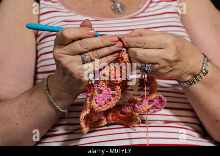 Weibliche Hände beschäftigt mit einem bunten Garne häkeln Projekt, Bild im Querformat Stockfoto