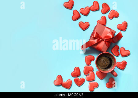 Valentinstag Karte. Geschenk mit roter Schleife, Tasse Kaffee und Herzen auf blauen Fläche. Ansicht von oben. Kopieren Sie Platz. Stockfoto