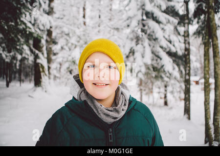 Lächelnden jungen im Wald im Schnee mit der Kamera schaut. Stockfoto