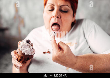 Übergewichtige Frau isst süße Kuchen, Faulheit und Übergewicht. Ungesunde Nahrung essen, Fettsäuren Weiblich Stockfoto