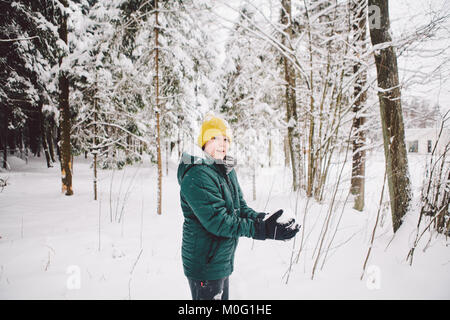 Teenager ist bereit, eine Handvoll Schnee in die Luft im Winter Wald zu werfen. Stockfoto